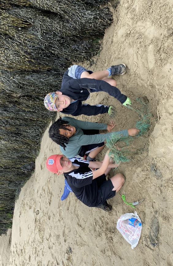 Three boys collecting rubbish on a beach