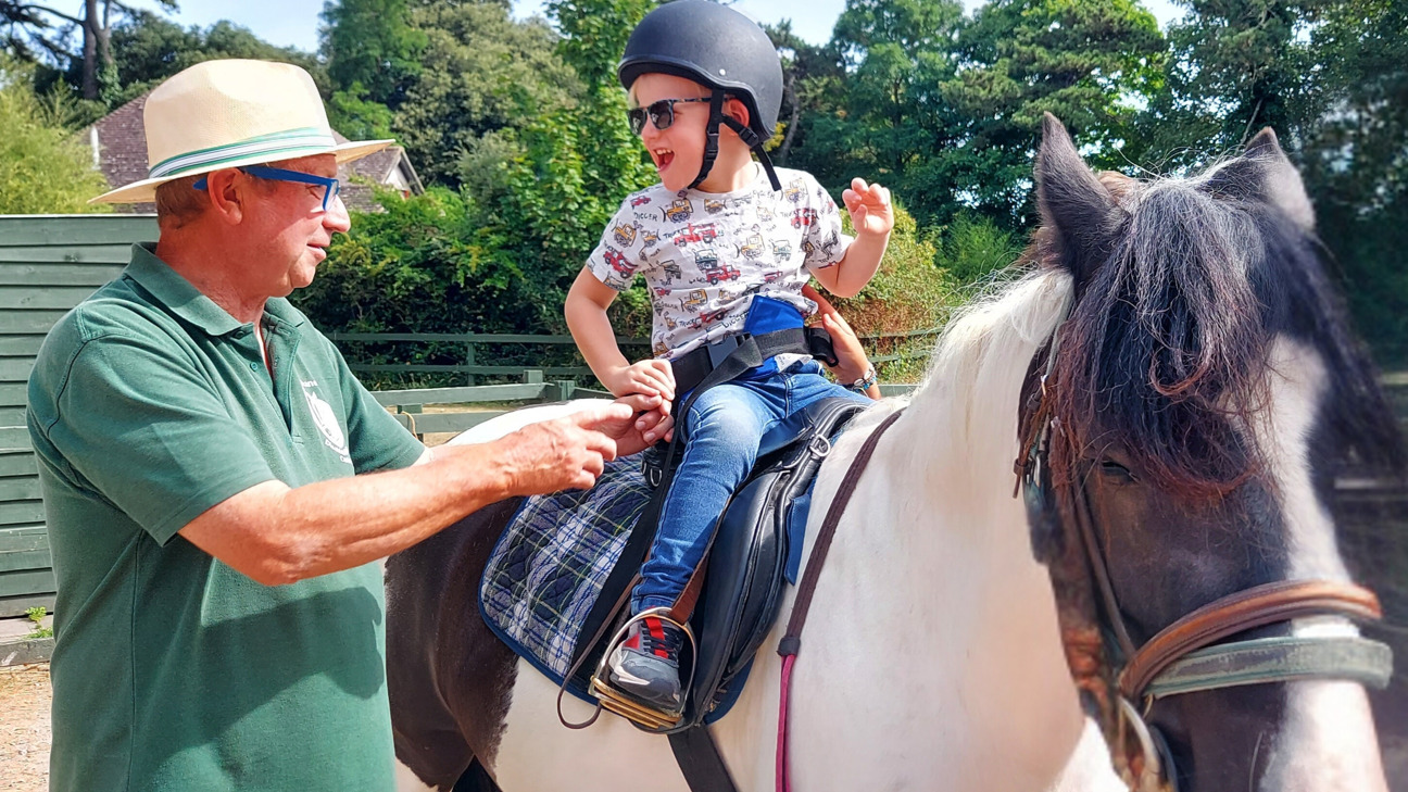 Thanet Disabled Riding Centre - boy riding a horse and being supported by a man