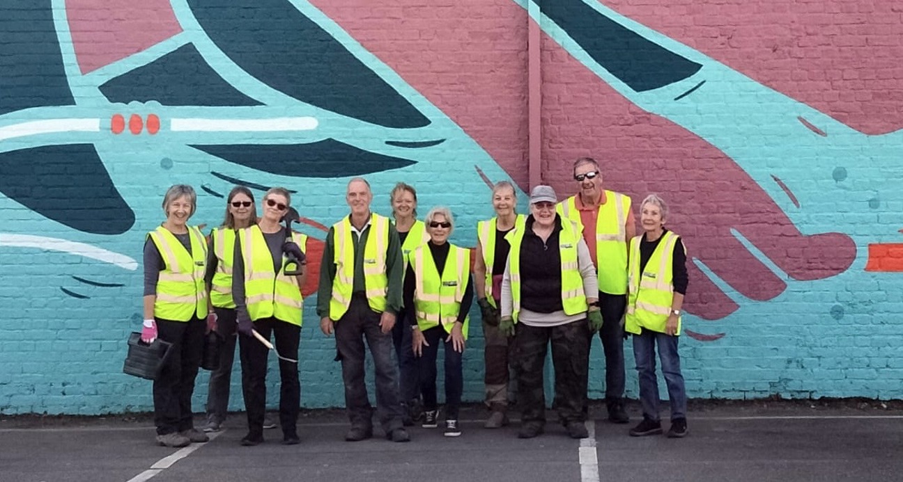 Gardening volunteers in front of murual
