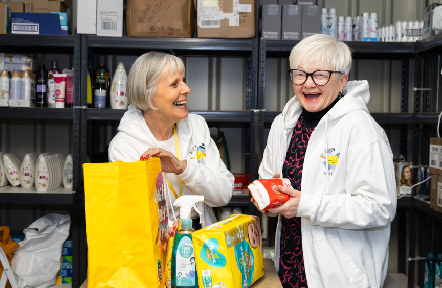 Two smiling female volunteers in a food bank
