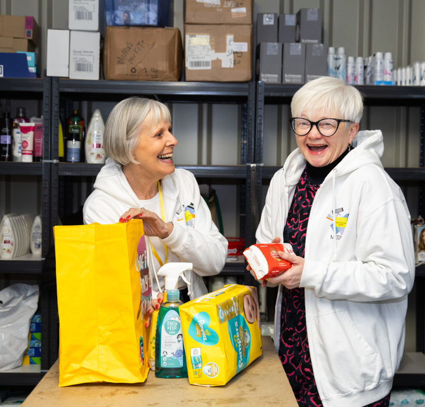 Two smiling female volunteers in a food bank